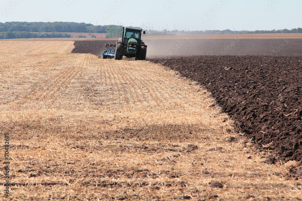 Fototapeta premium Tractor plows the land
