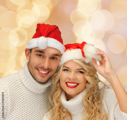 smiling couple in sweaters and santa helper hats