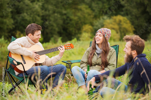 group of smiling friends with guitar outdoors © Syda Productions