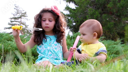 Cute girl and her little brother having fun with soap bubbles photo