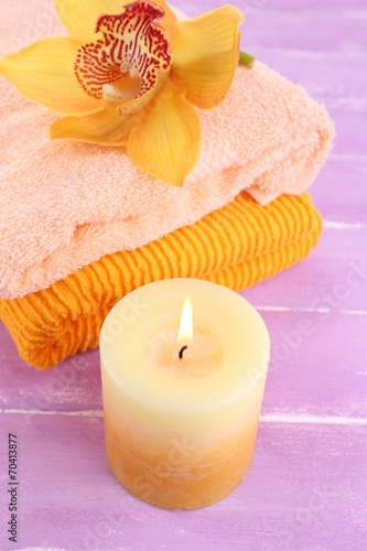 Orchid flower and towels on color wooden background