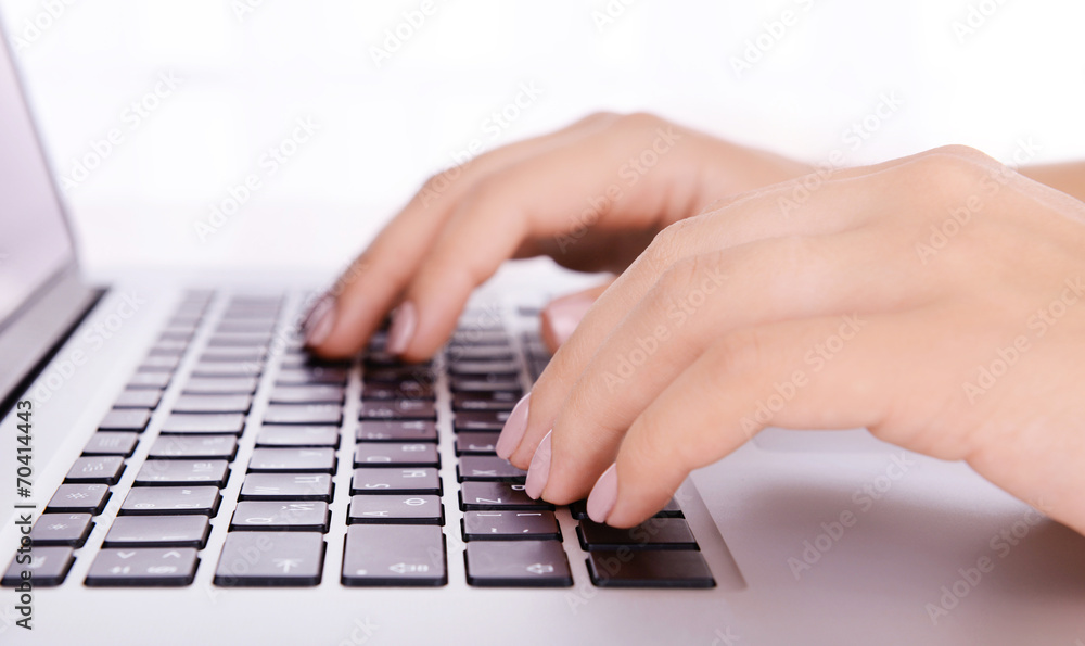 Female hands working on laptop on light background Female hands working on laptop on light background