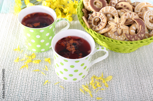 Two polka dot cups of tea with biscuits on fabric background