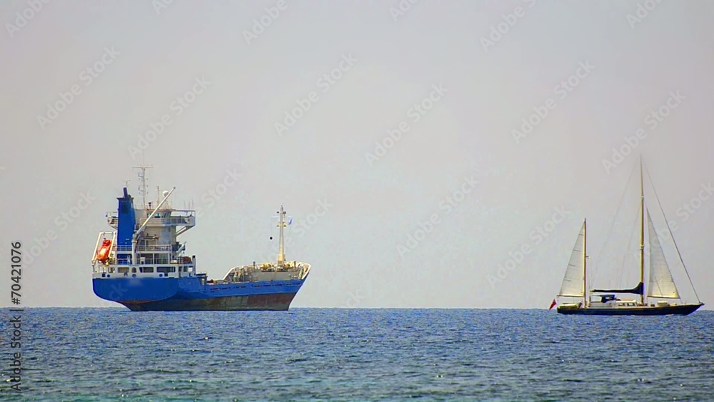 Sailboat is passing near transportation tanker boat Sailboat is passing near transportation tanker boat