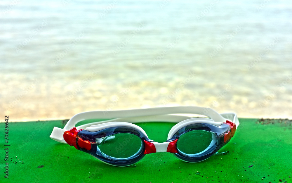 Blue and red goggles by the sea