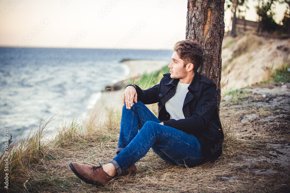young man on sea background. autumn beach