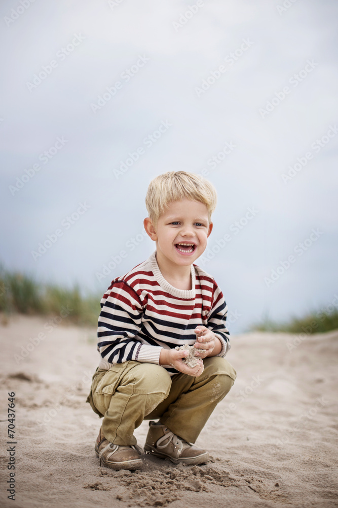 Beautiful boy playing with sand on the beach Beautiful boy playing with sand on the beach