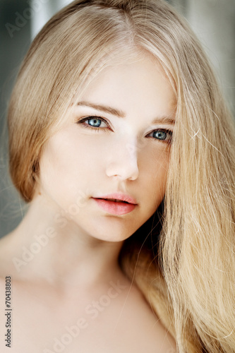 Woman face close up. A pretty young blond trendy. Girl with a be