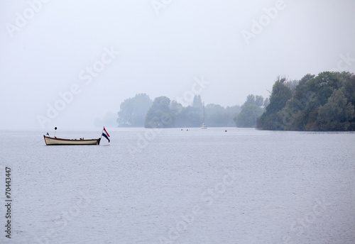 Fishing boat with Dutch flag on the Westeinder Plassen lake in Aalsmeer, Noord Holland - The Netherlands - Europe photo