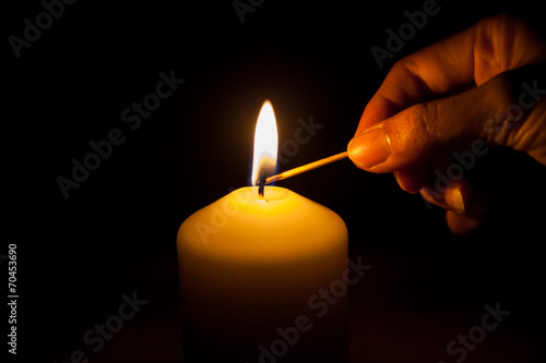 hand with matchstick, lighting a candle