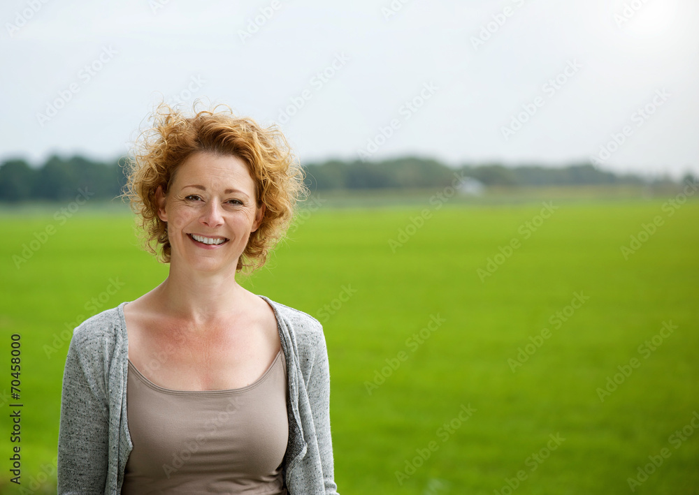 Attractive woman smiling outdoors by green countryside Attractive woman smiling outdoors by green countryside