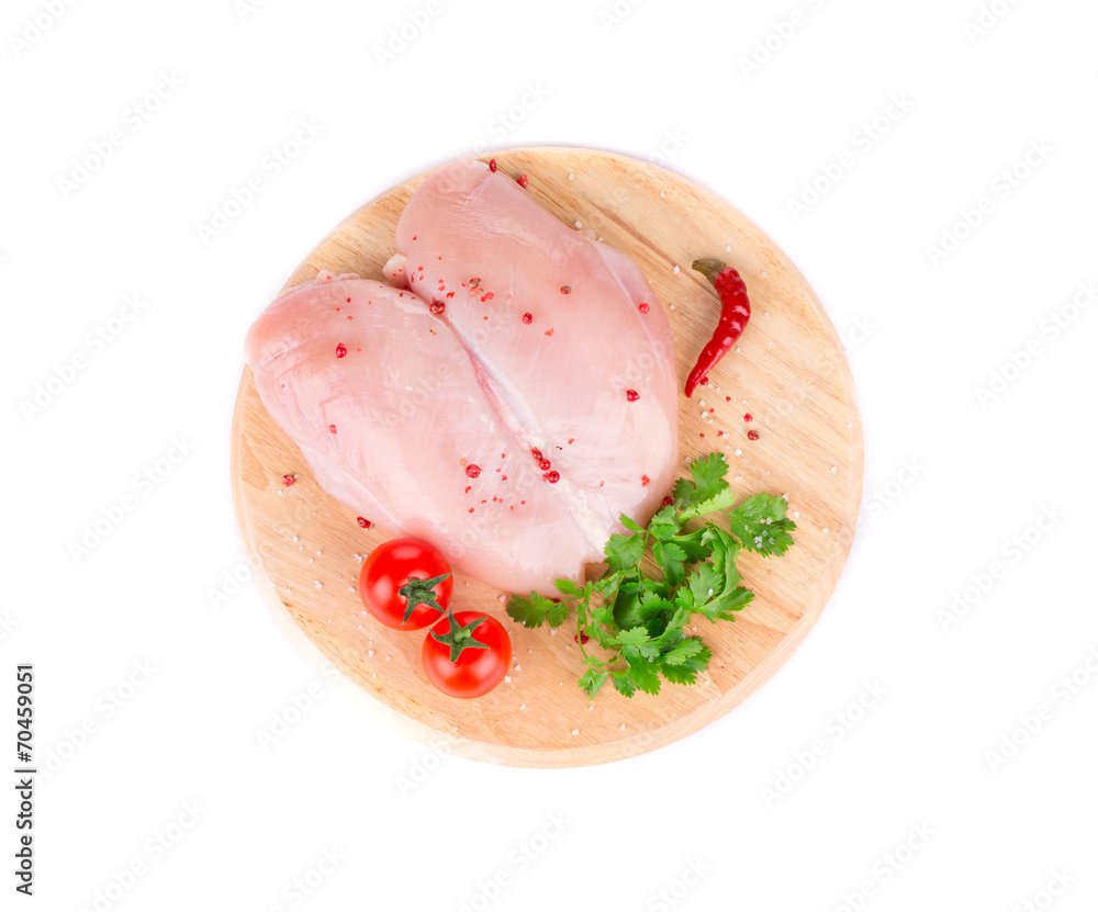 Raw chicken breast on wooden platter.