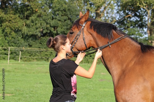 Junge Frau kontrolliert Zügel bei ihrem Pferd © fotospirale
