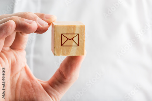 Hand holding a wooden block with an envelope icon