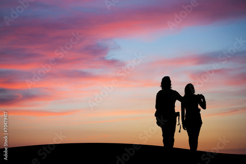 silhouetted couple watching sunset sky