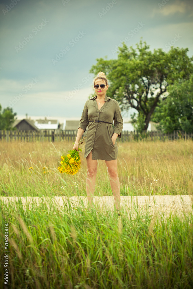 girl in a green dress standing with a bouquet of yellow flowers