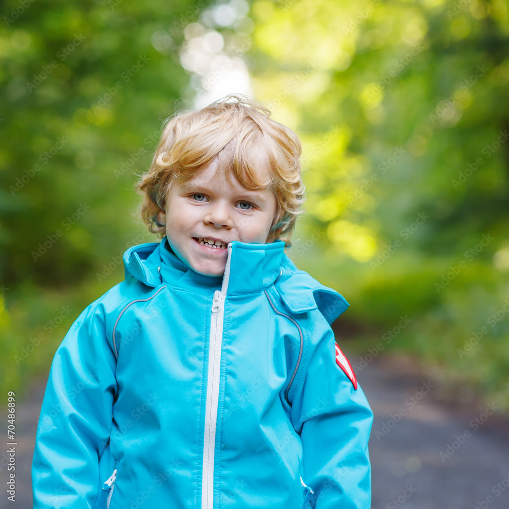 Portrait of blond little toddler boy in blue waterproof raincoa Portrait of blond little toddler boy in blue waterproof raincoa