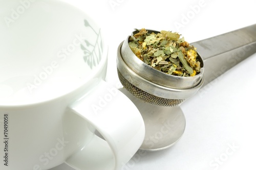 Teesieb mit einer Heilkräutermischung und Tasse