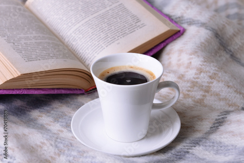 Cup of coffee on plaid with book