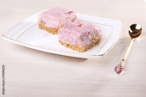 Cakes on plate with spoon on wooden background