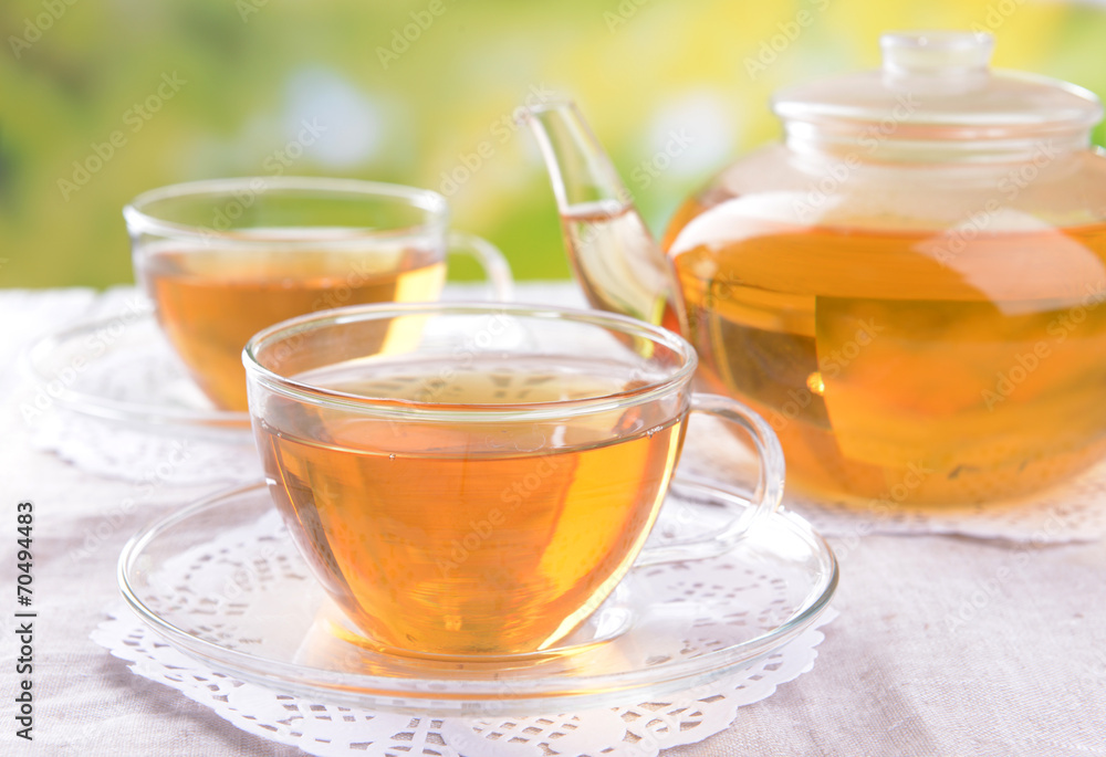 Teapot and cups of tea on table on bright background Teapot and cups of tea on table on bright background