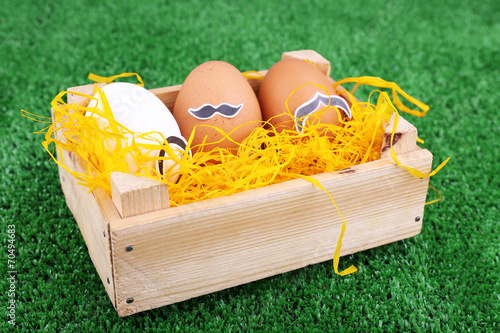 Eggs in wooden box on green background