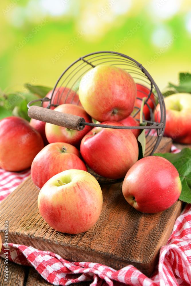 Sweet apples in wicker basket on table on bright background Sweet apples in wicker basket on table on bright background