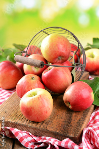 Sweet apples in wicker basket on table on bright background