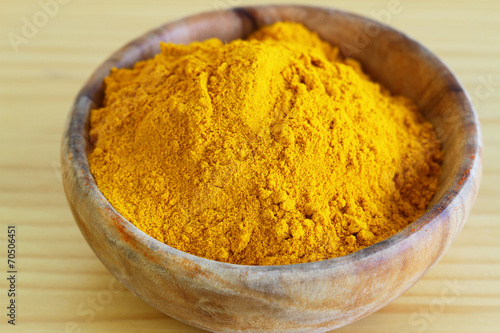 Tumeric powder in wooden bowl, close up