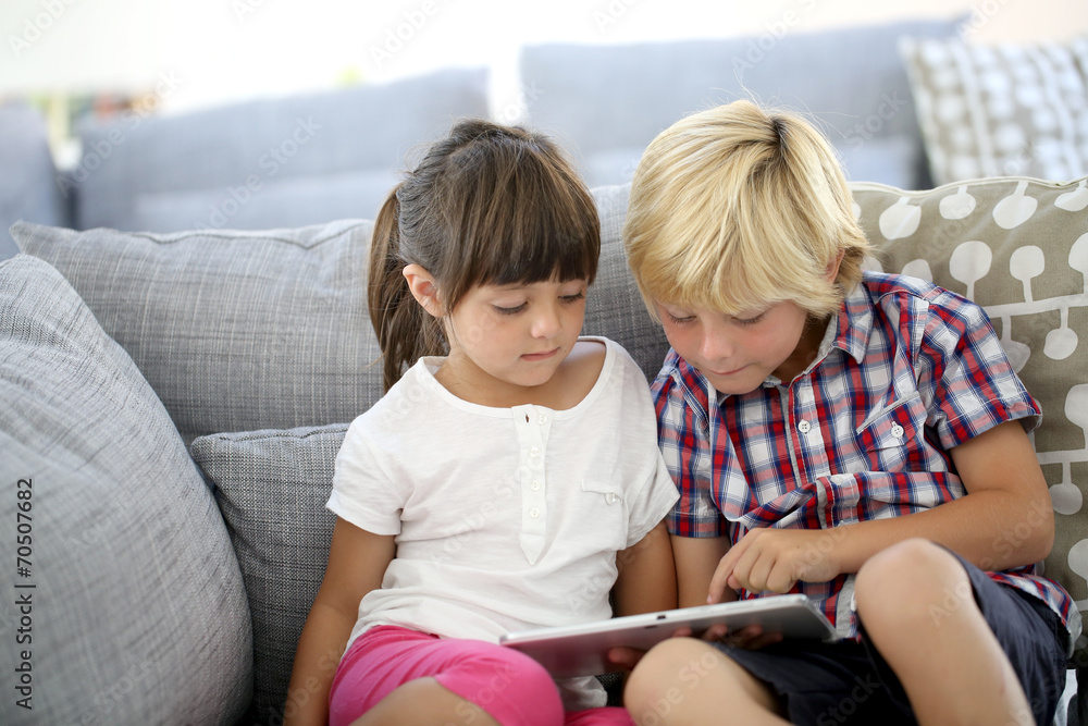 Kids sitting in sofa and playing with tablet Kids sitting in sofa and playing with tablet