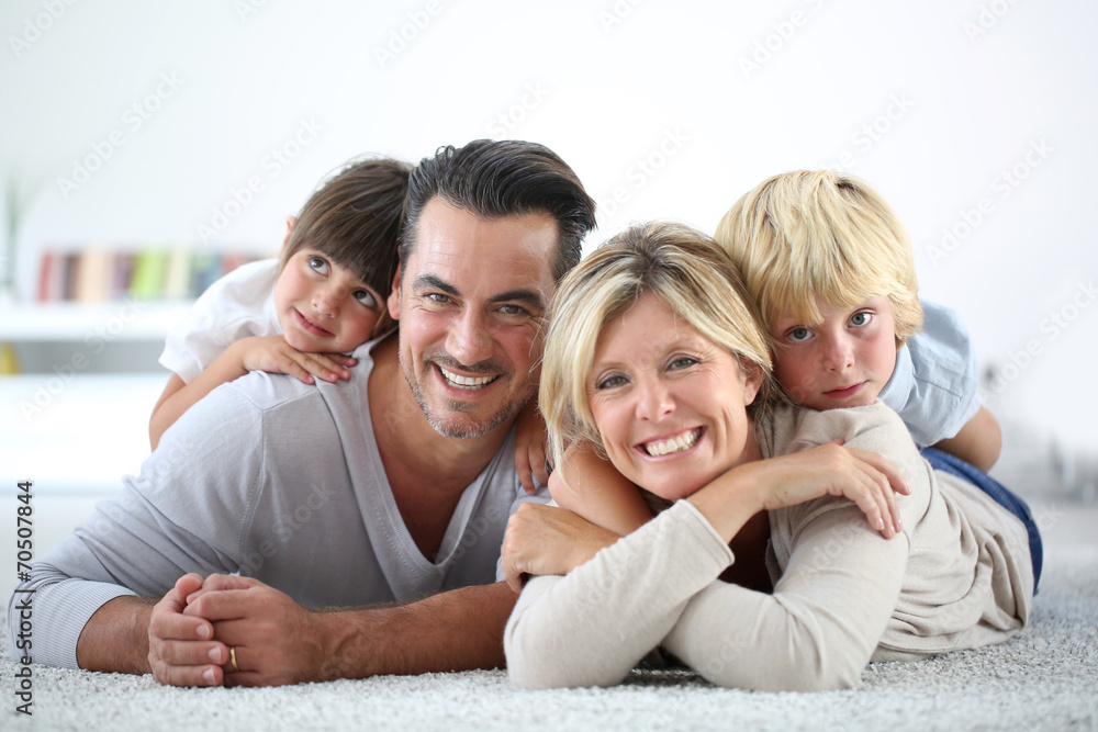 Portrait of happy family laying on carpet - obrazy, fototapety, plakaty 