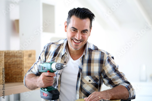 Fotografie Man at home using electric drill