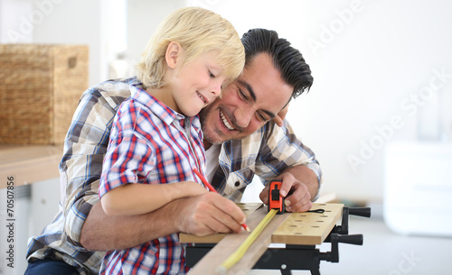 Father with kid measuring wood plank photo