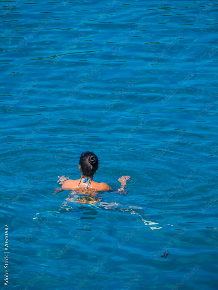 Beautiful girl swimming in blue water