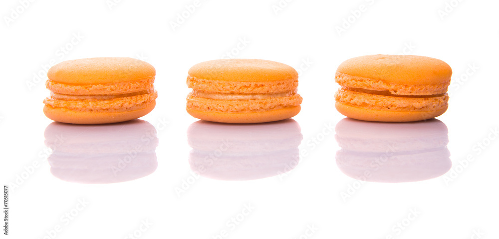 Orange colored French macarons over white background