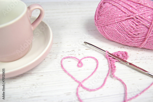 pink crochet background with yarn heart and coffee cup
