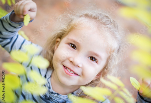 happy little girl among yellow leaves in autumn