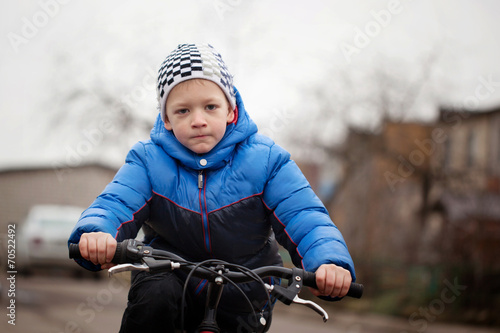 Portrait of a little girl on a bicycle in the cold autumn