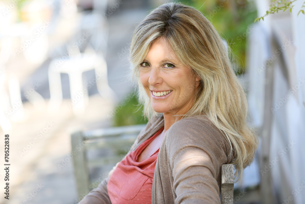 Mature blond woman relaxing in outdoor bench