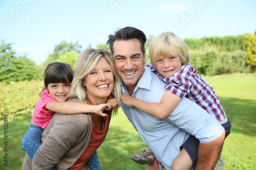 Parents giving piggyback ride to kids in park