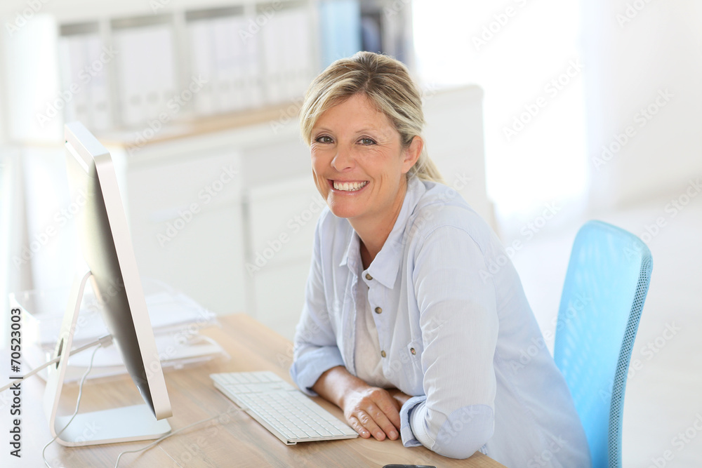 Mature businesswoman sitting in front of desktop Mature businesswoman sitting in front of desktop