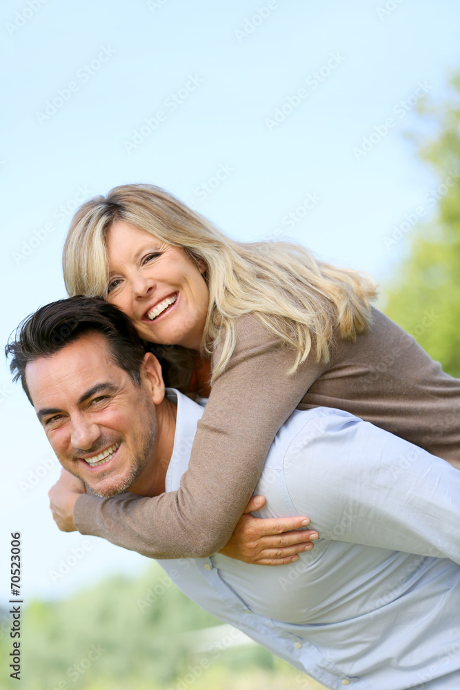 Cheerful mature man giving piggyback ride to woman Cheerful mature man giving piggyback ride to woman
