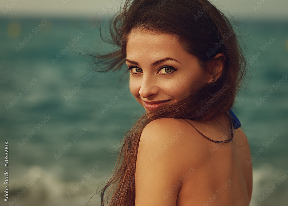 Smiling young woman looking happy on sea background