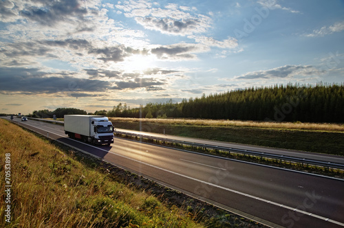 Shining sun over the highway, white truck on the road