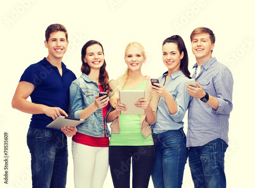 smiling students using smartphones and tablet pc