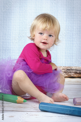 Little girl sitting on the floor with big crayons photo