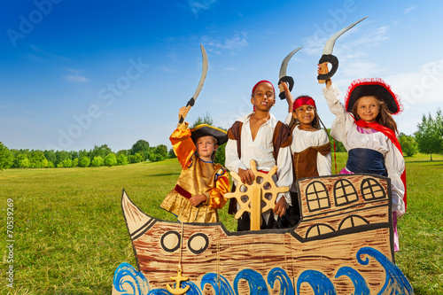 Four kids in pirate costumes behind ship