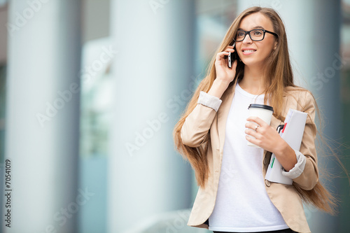 Successful businesswoman with cellphone while walking outdoor. C