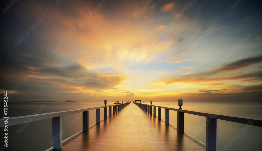 Obraz premium Lesisty most w porcie między wschodem słońca.