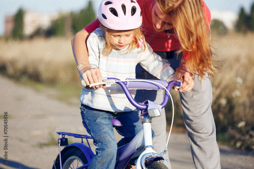 Obraz premium Redhead girl in helmet learning riding bike.